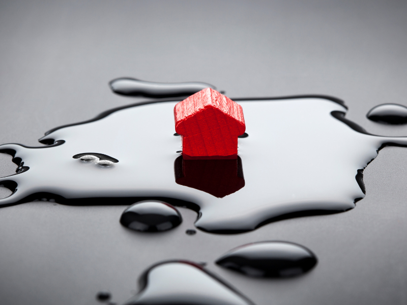 Image of a small wooden house in a puddle of water to represent house flooding
